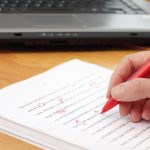 hand with red pen editing manuscripts