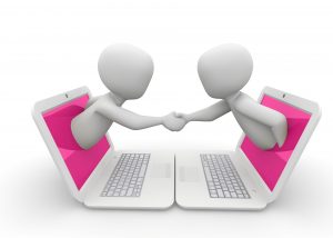 two figures emerging from laptops and shaking hands from the screens of their laptops