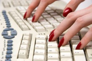 fingers with red fingernail polish on computer keyboard