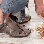 feet in tattered shoes homeless man reaches for coins